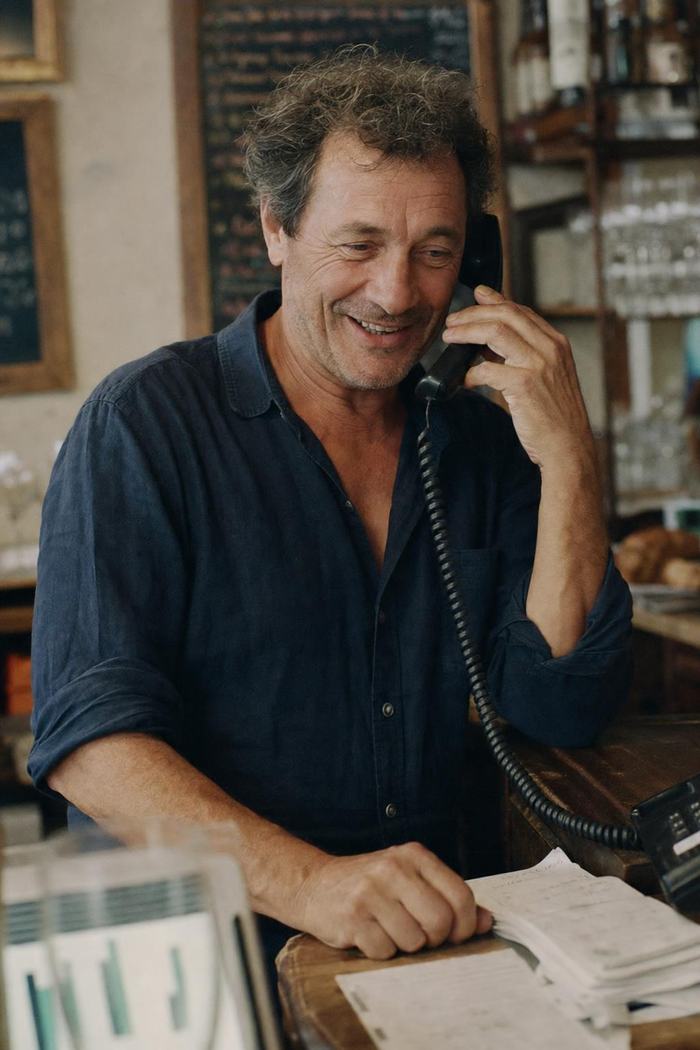 Le patron d’un bistrot prend une réservation au téléphone au bout du comptoir